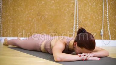 年轻女子躺在垫子上，慢动作在瑜伽馆做瑜伽练习